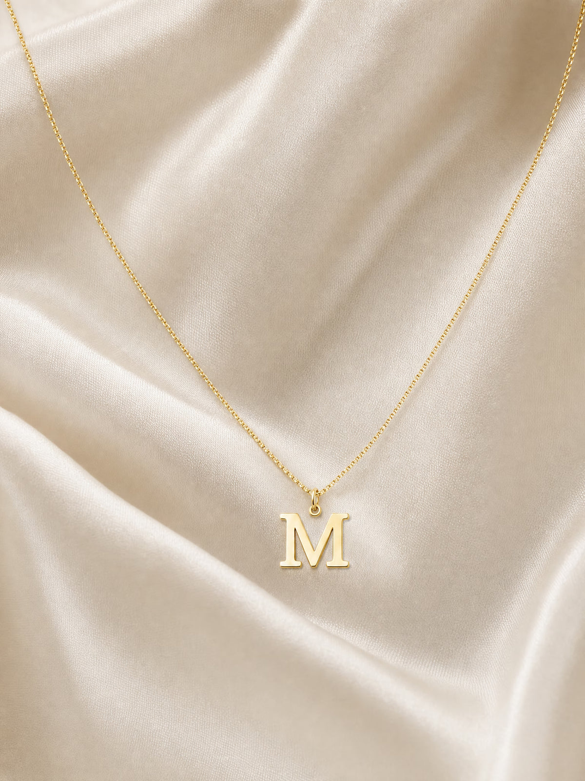 SAINT GILD initial necklace flatlay on satin