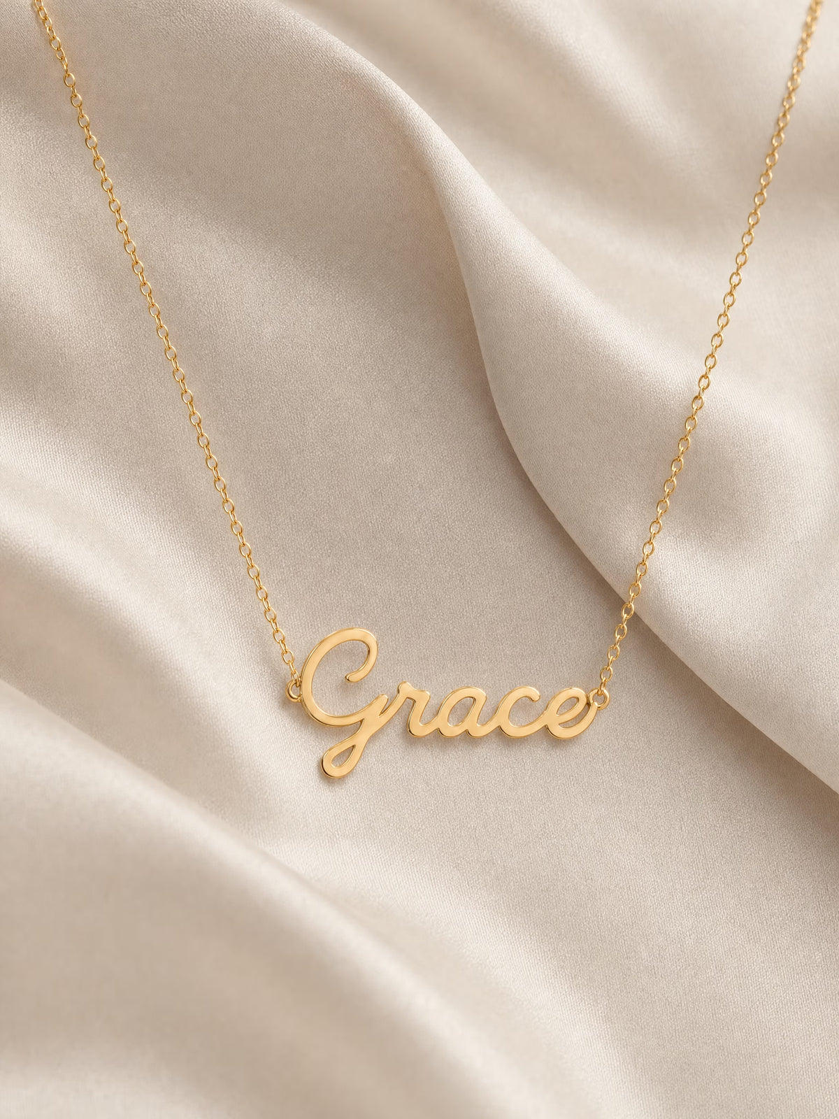 SAINT GILD name necklace flatlay on satin