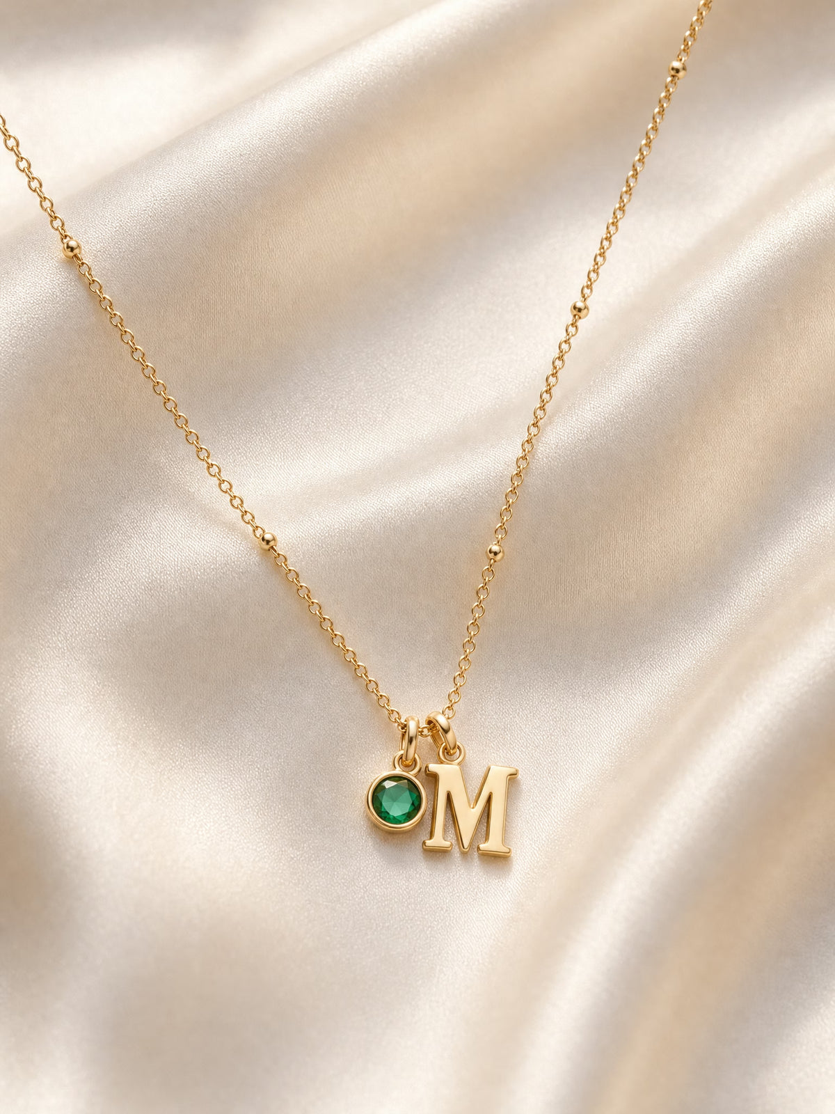 SAINT GILD initial birthstone necklace flatlay on satin