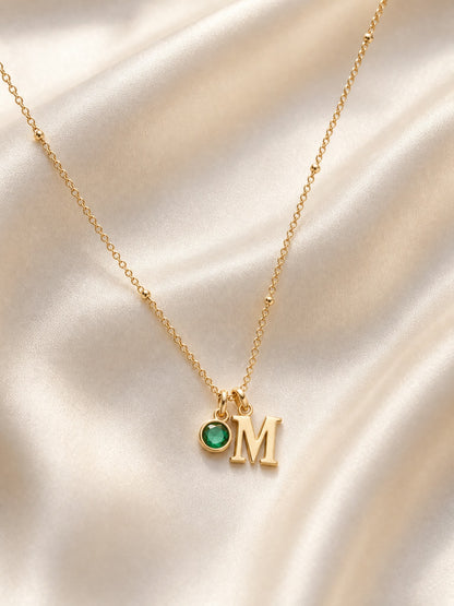 SAINT GILD initial birthstone necklace flatlay on satin