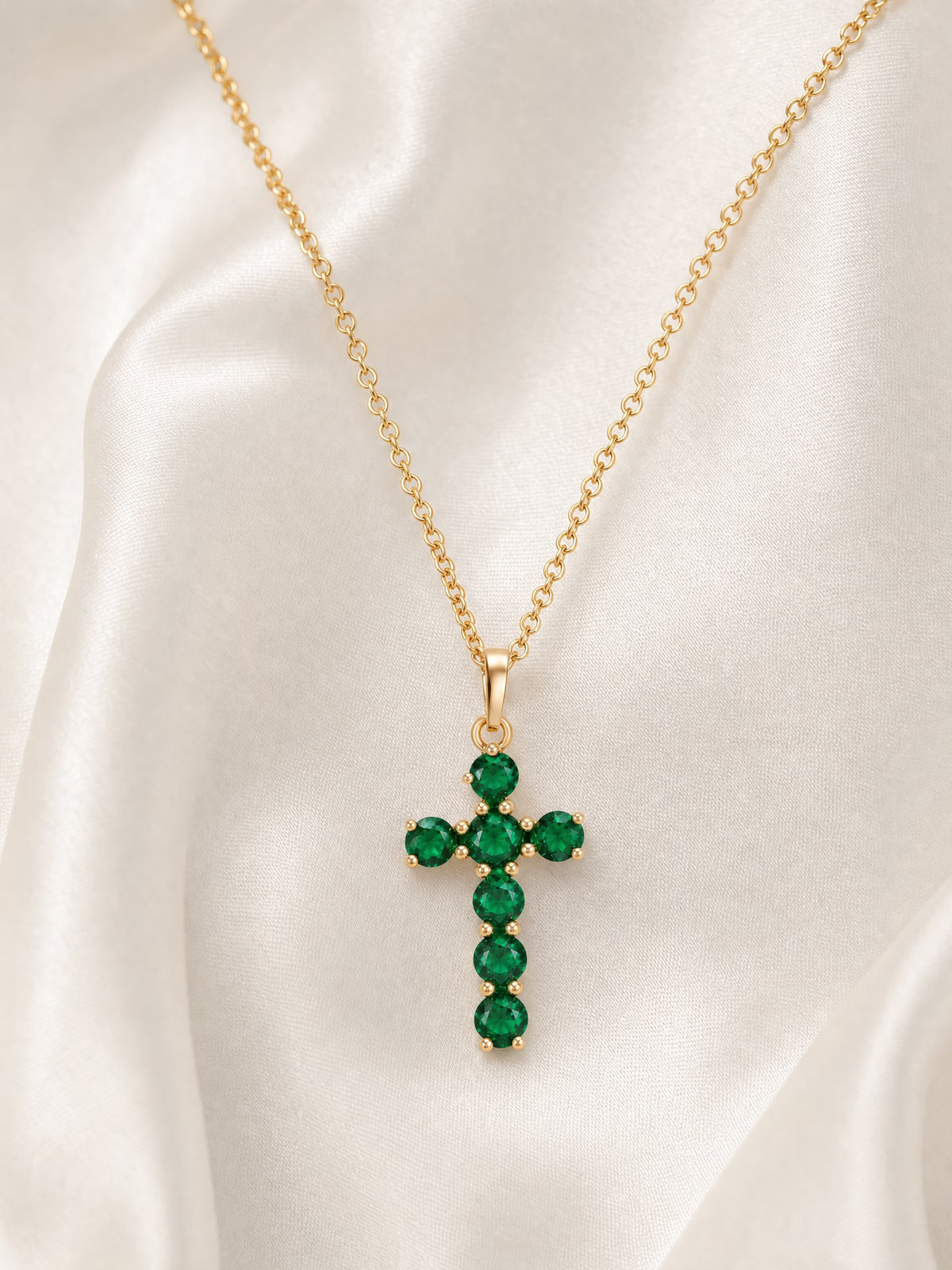 SAINT GILD birthstone cross necklace flatlay on satin
