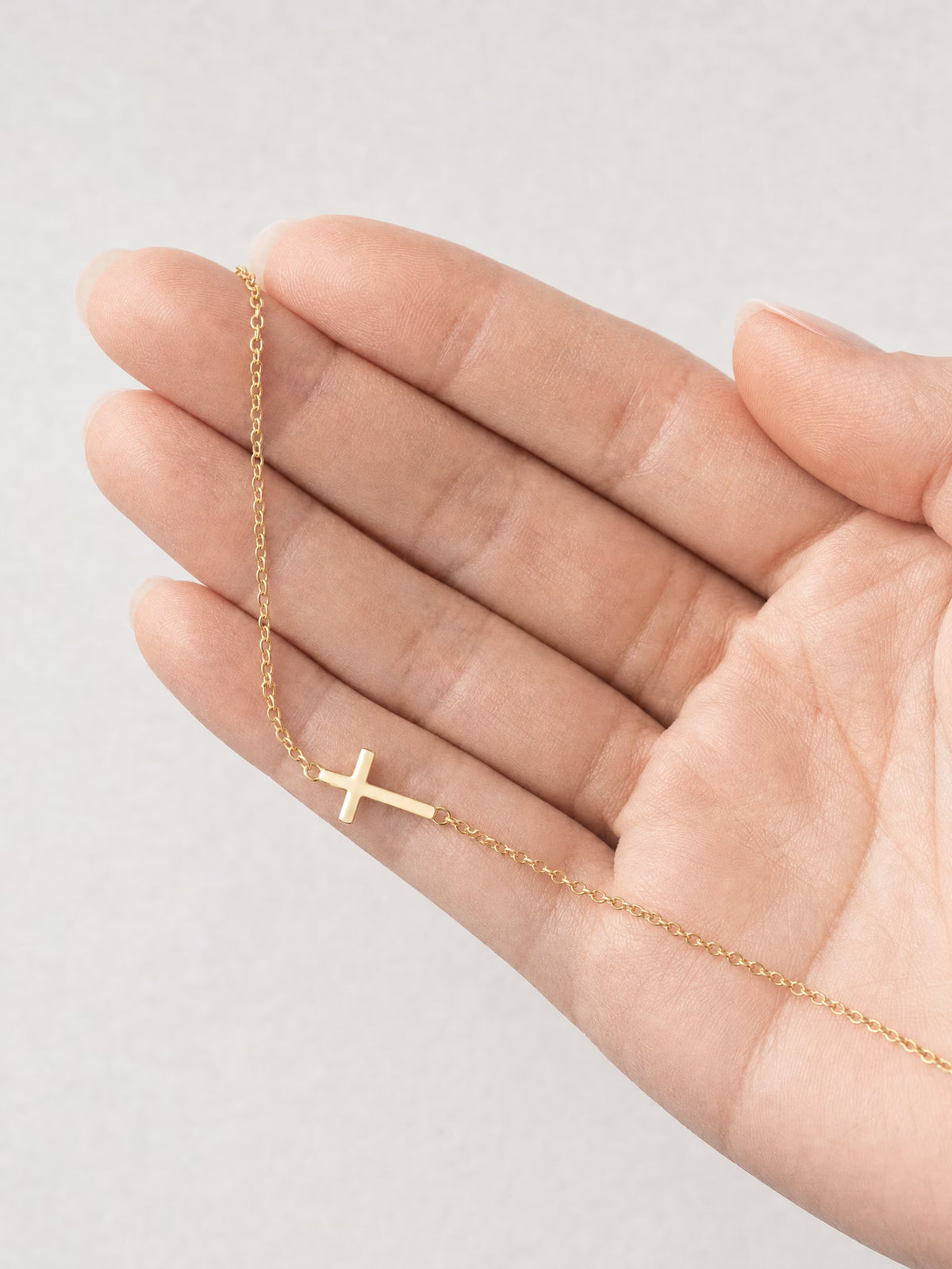 SAINT GILD Sideways Cross Necklace in hand